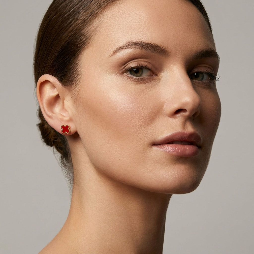 Red clover earring on a model's earlobe, gold-tone border against fair skin