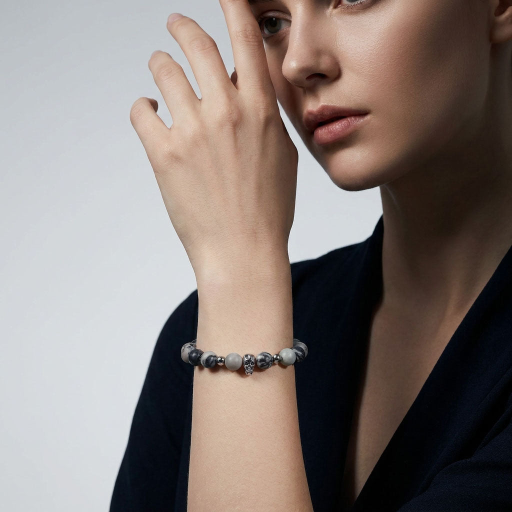 Stone bead bracelet with a skull on a woman's wrist beside dark clothing