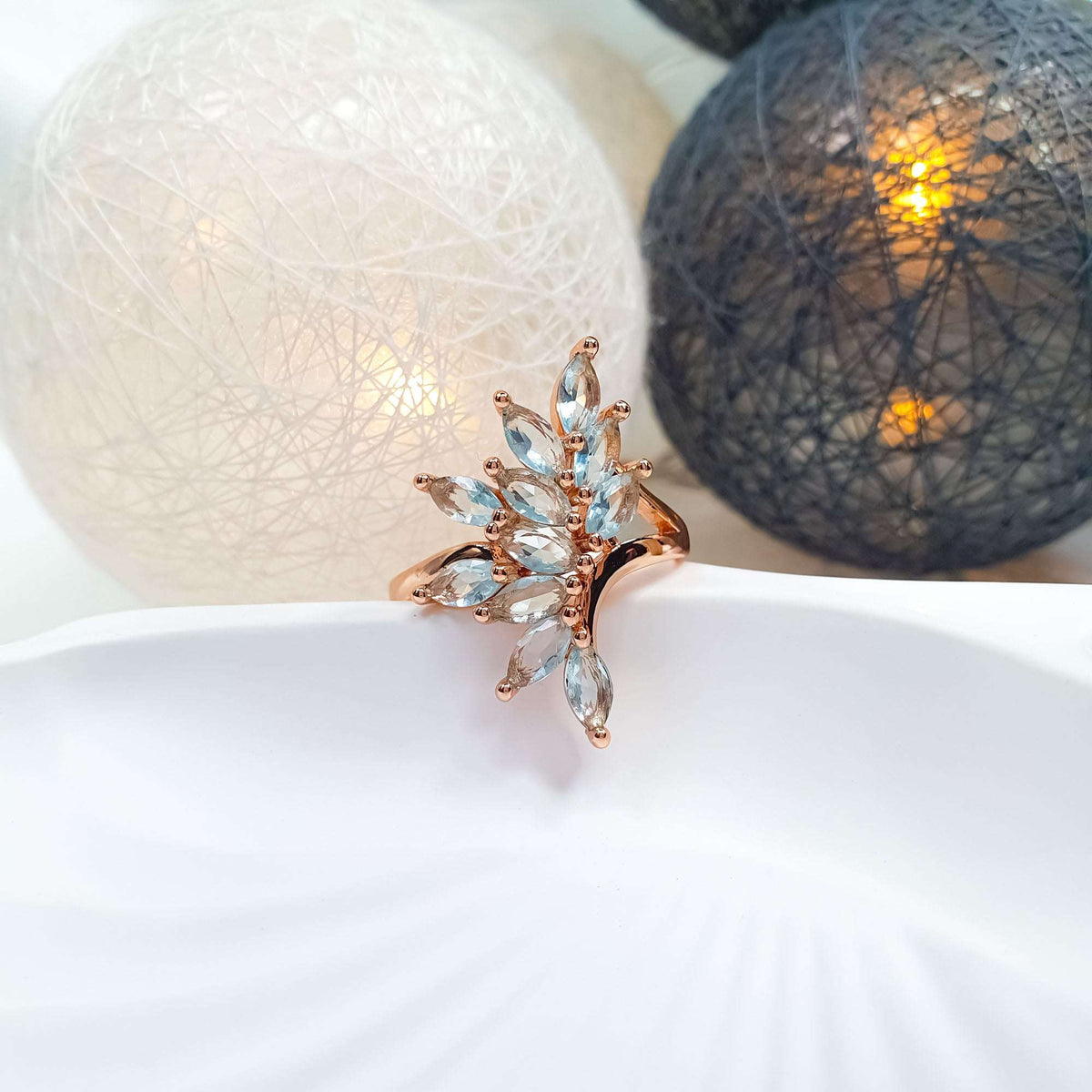 Gold-tone ring with a fan of light blue stones on a white plate