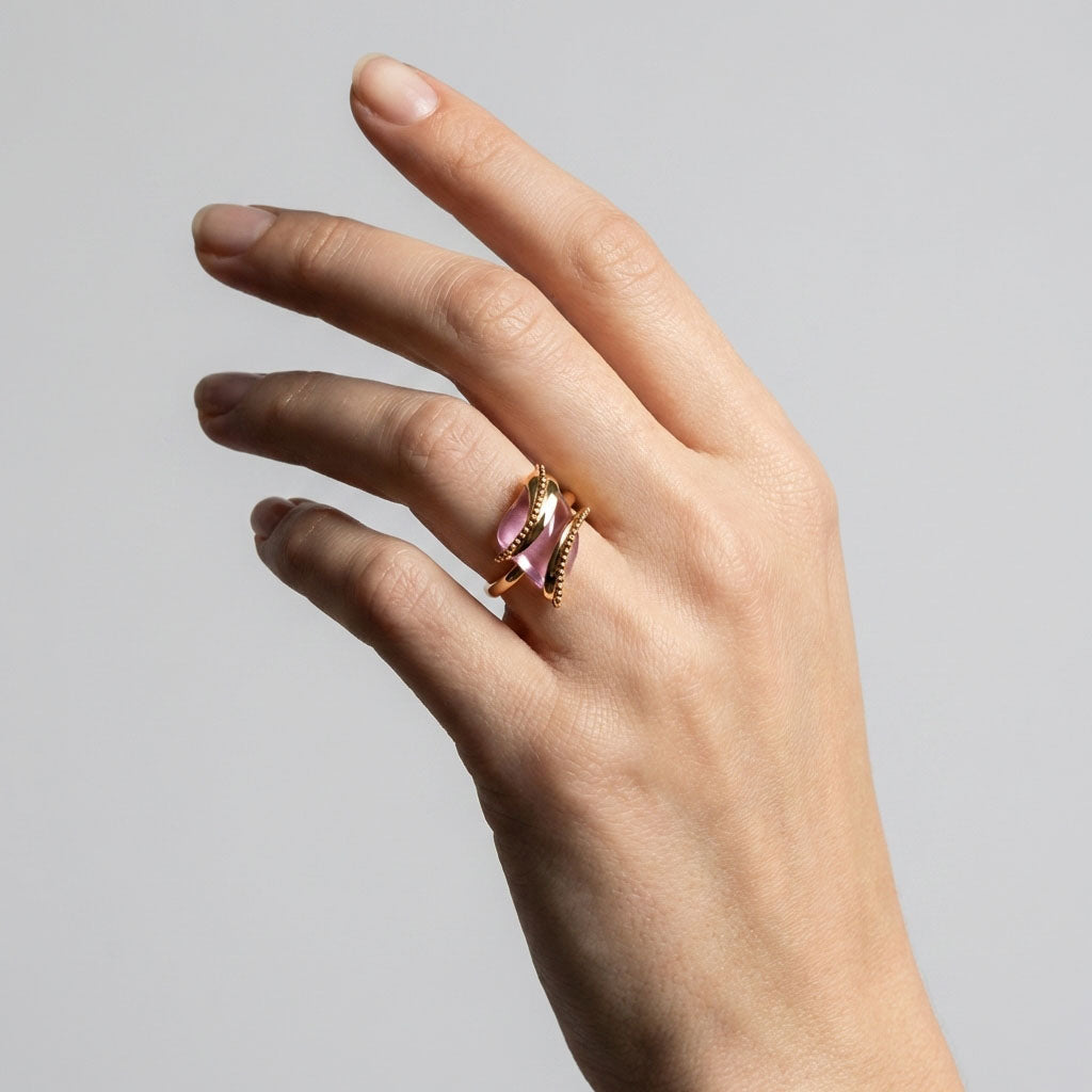 Pink stone ring on a woman's finger showing the gold-tone spiral pattern