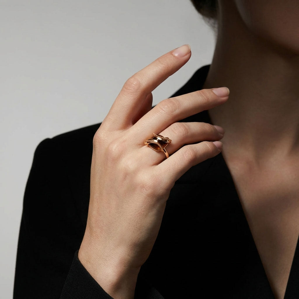 Coffee-coloured cubic zirconia ring on a model's finger, black jacket, grey background
