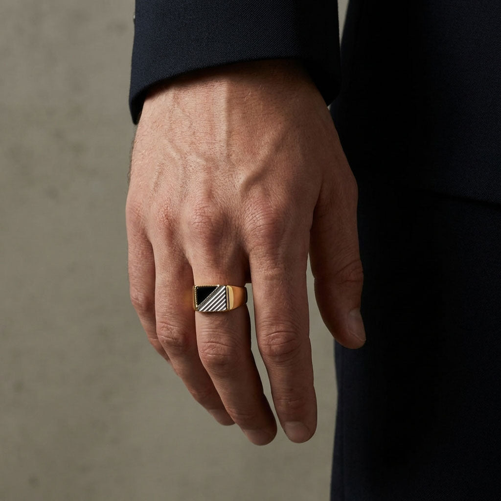 Man in a dark suit wearing a gold-plated signet ring with black inlay