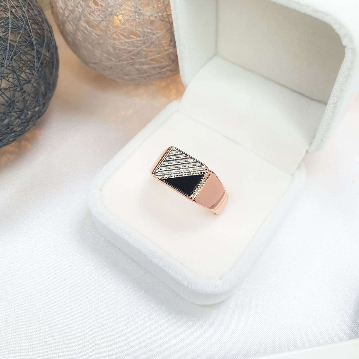 Signet ring with a black triangular inlay in a white velvet gift box