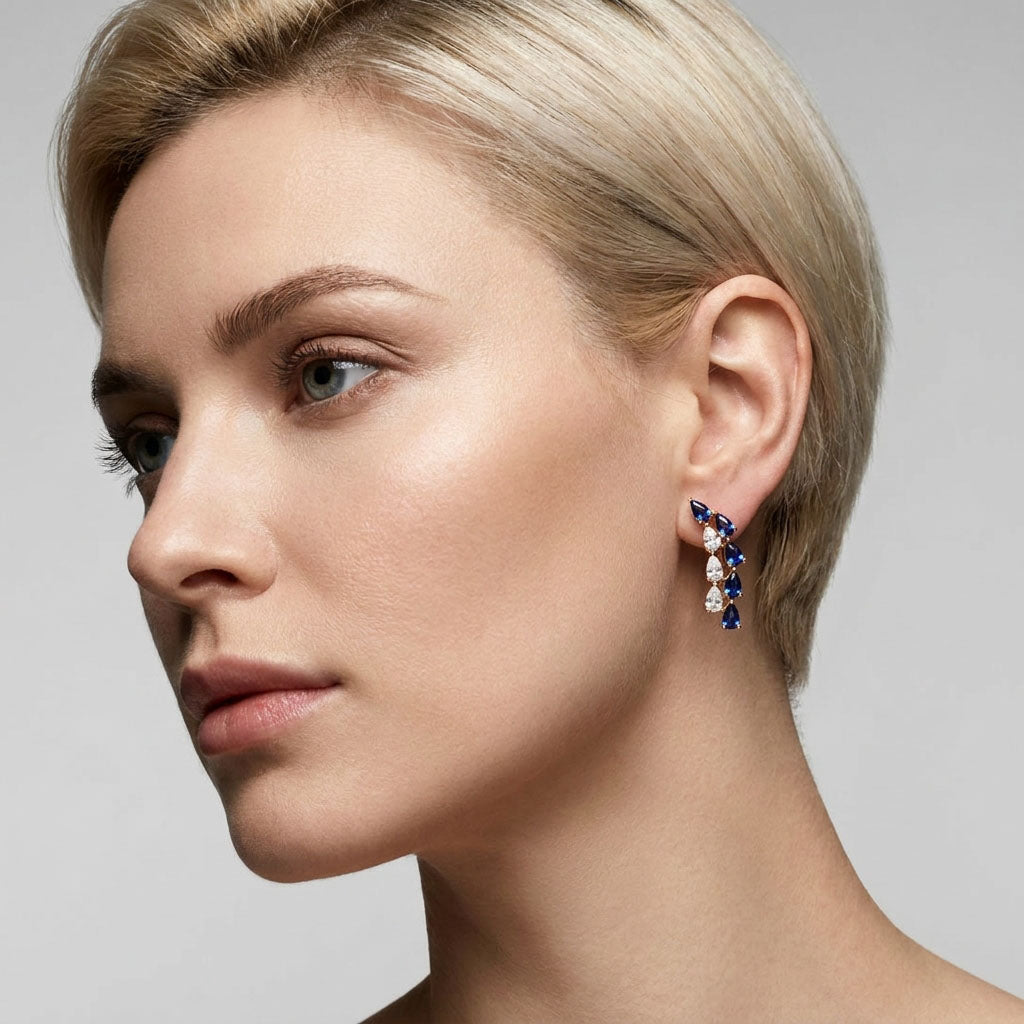 Model in profile wearing blue and white cubic zirconia earrings that follow the ear