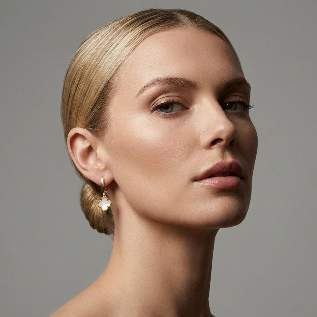Model with her hair up wearing a gold-tone clover earring with a pearly inlay