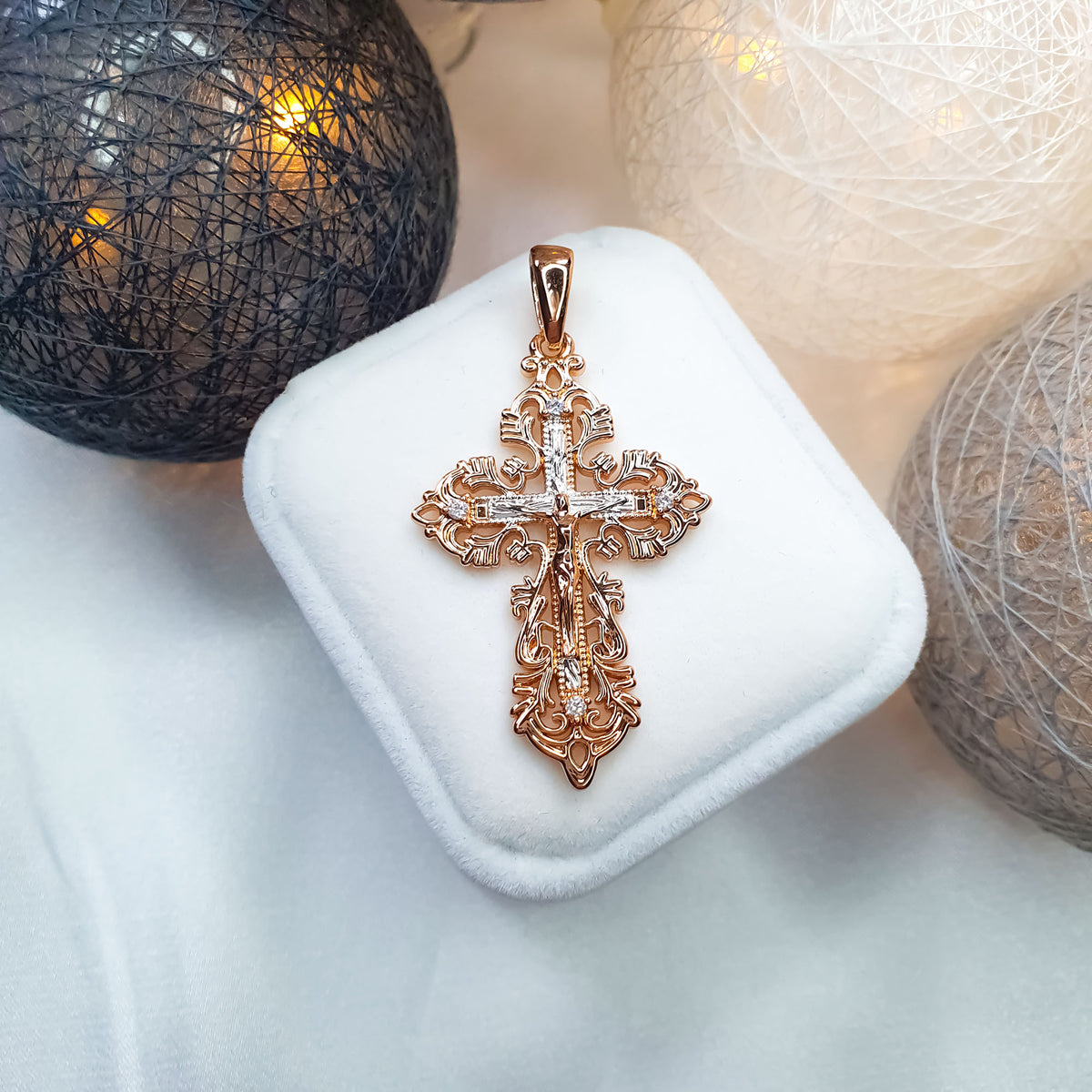 Two-tone cross pendant with cubic zirconia on a white case in soft light