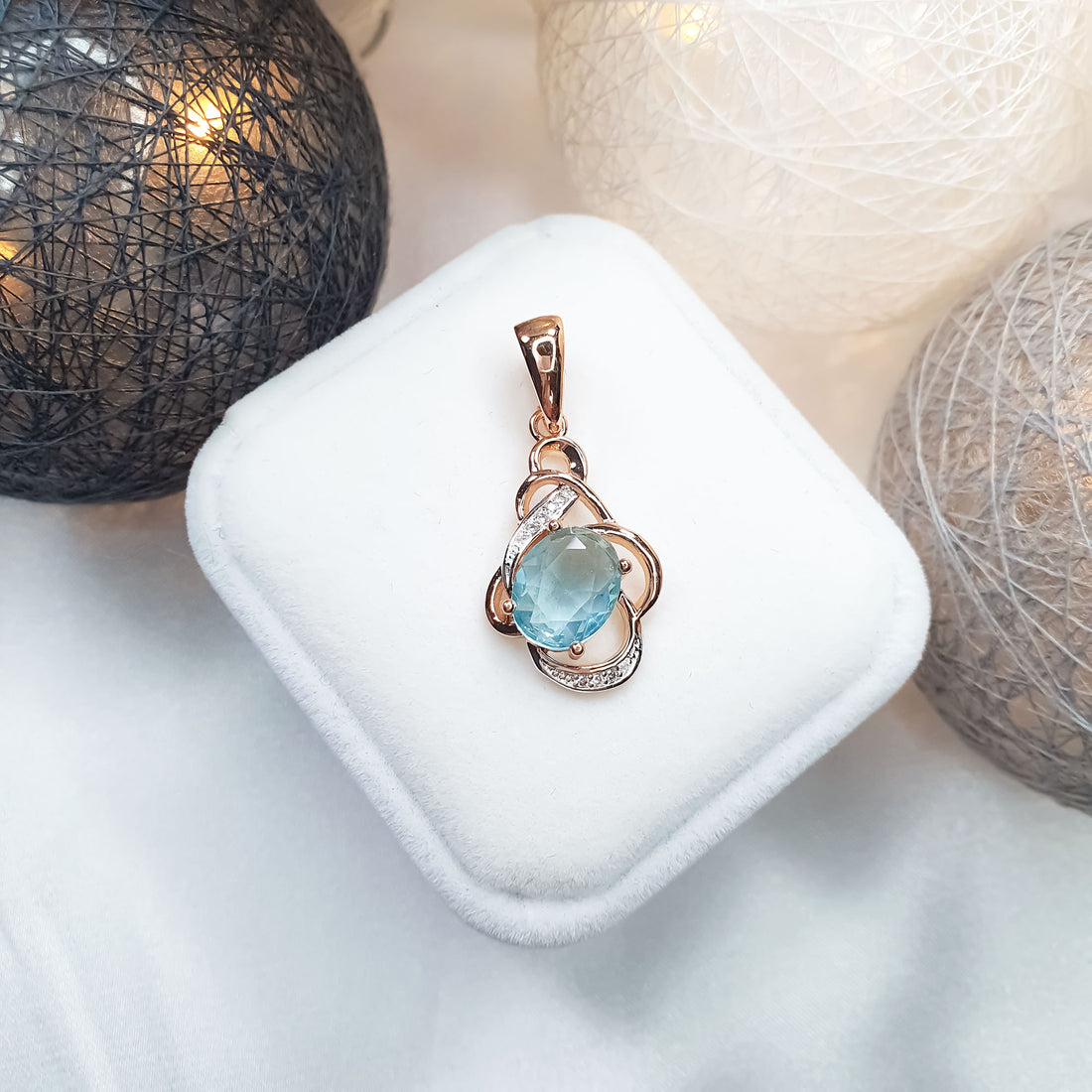 Light blue cubic zirconia pendant in a gold-plated frame on a velvet box