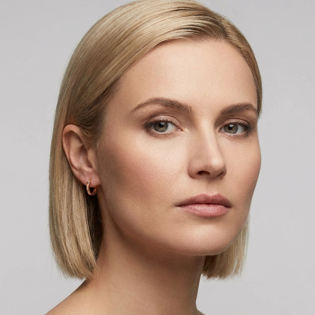 Side close-up of a model wearing a fine rose gold tone hoop