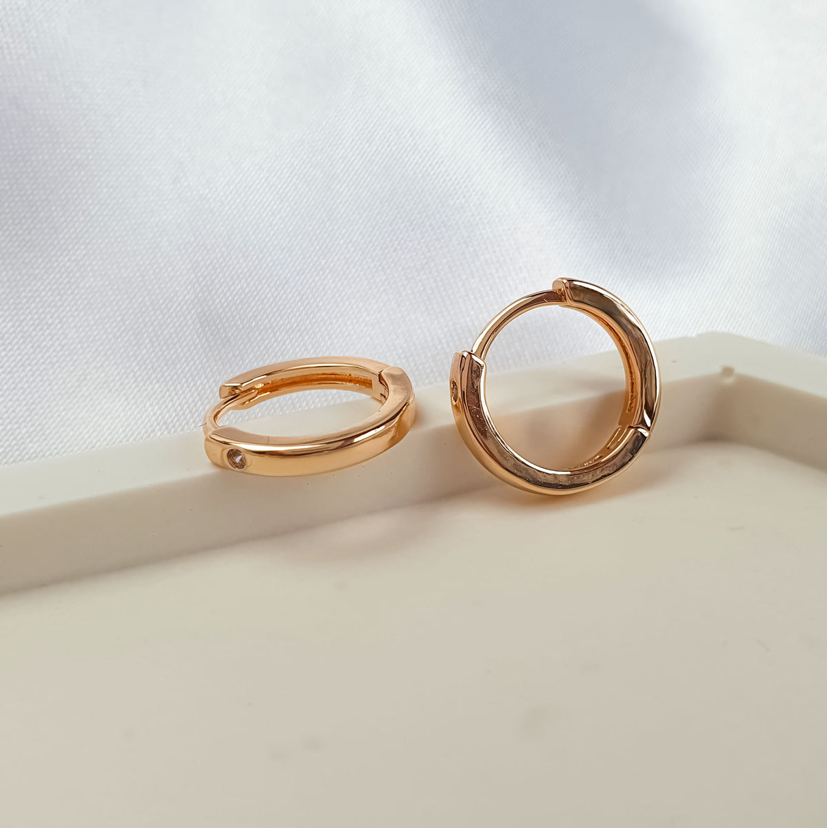 Two hoop earrings close up showing the hinged closure and cubic zirconia