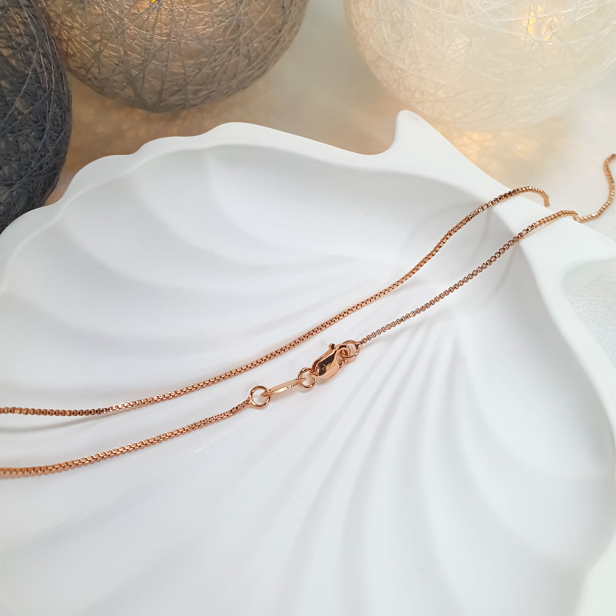 Gold-tone chain on a white shell-shaped dish in warm light