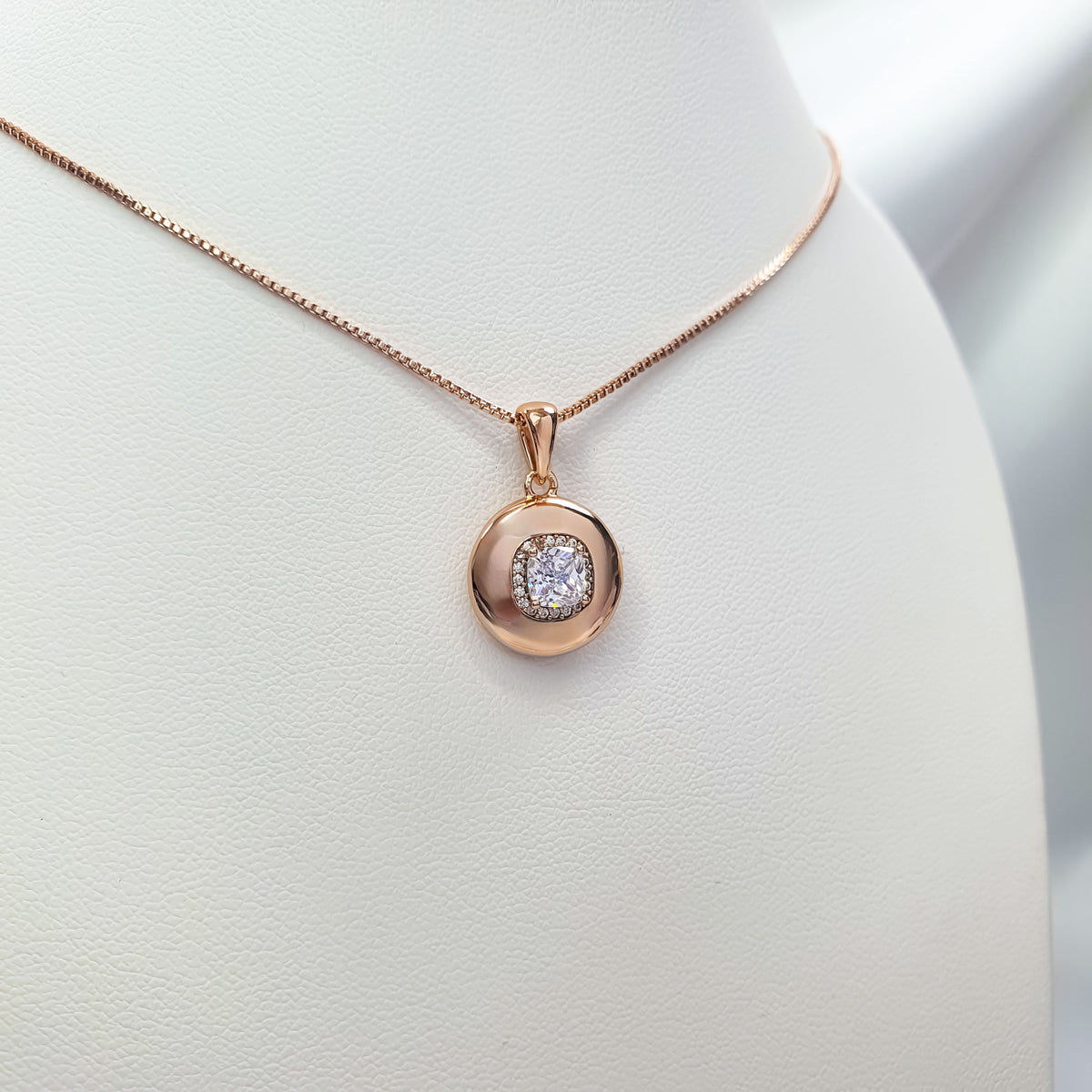 Close-up of rose gold-tone pendant with sparkling cubic zirconia on a white stand
