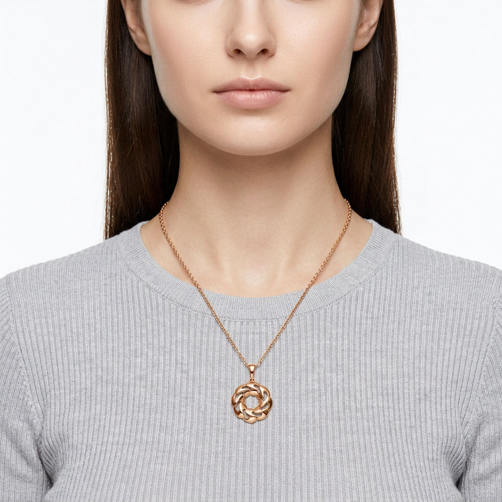 Model in a grey jumper wearing round pendant on a fine gold-tone chain