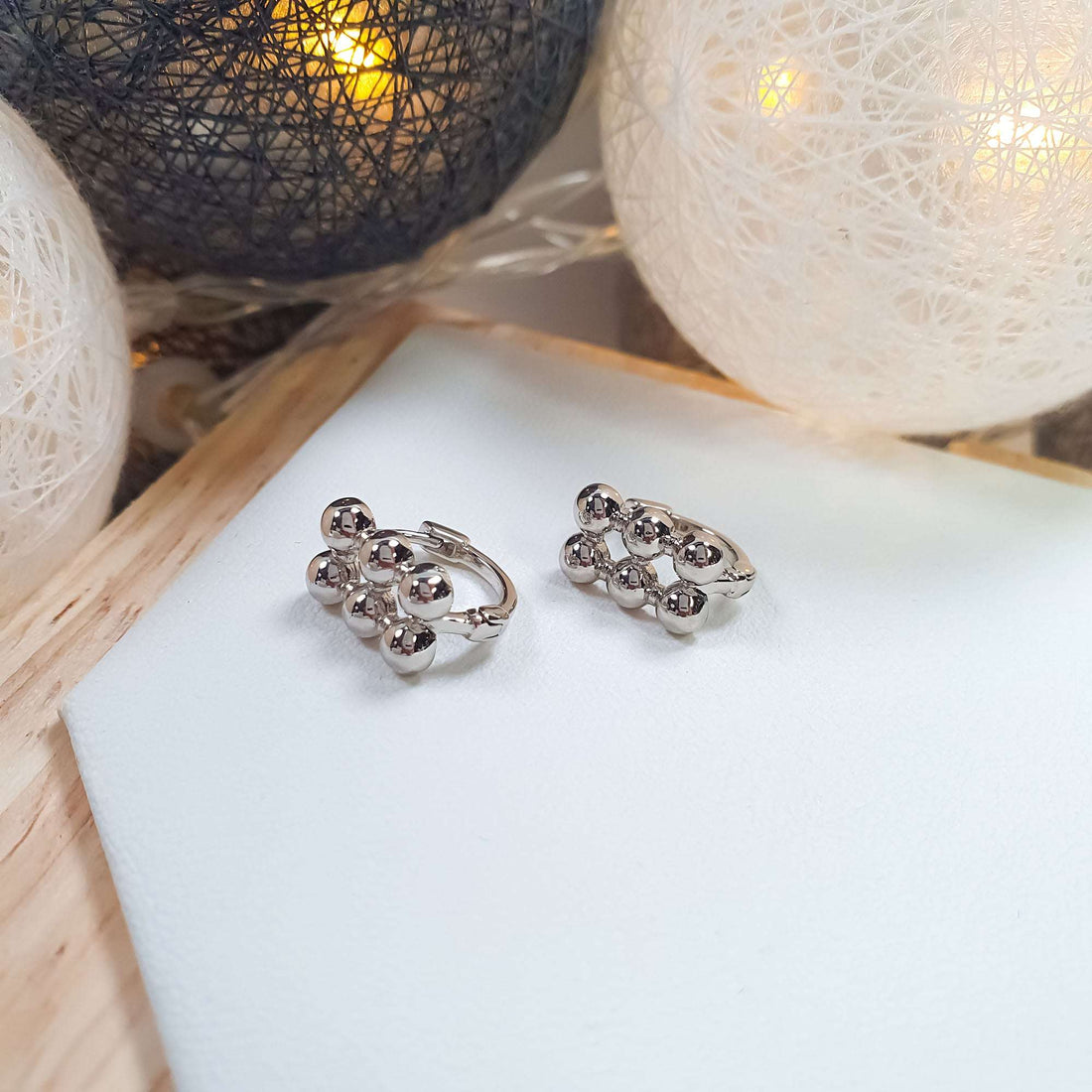 Silvery platinum-plated hoop earrings with three rows of balls on the front