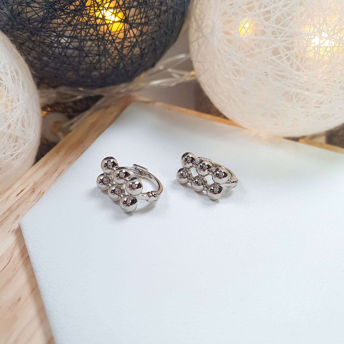 Silvery platinum-plated hoop earrings with three rows of balls on the front