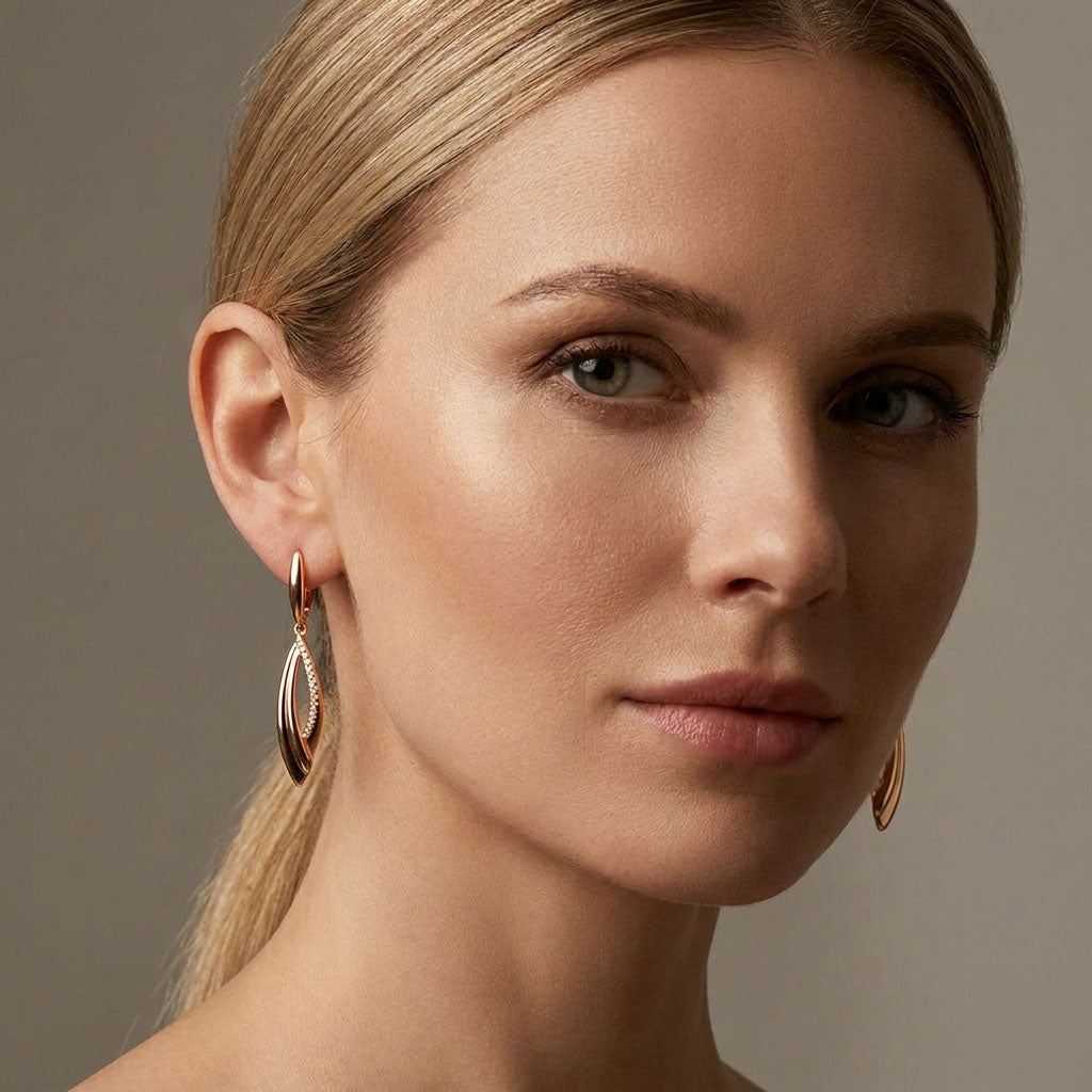 Model wearing long gold-plated earrings, close-up of the curved drop shape at the ear