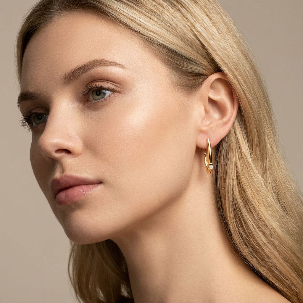 Model wearing V-shaped gold-plated earrings, cubic zirconia sparkling at the earlobe
