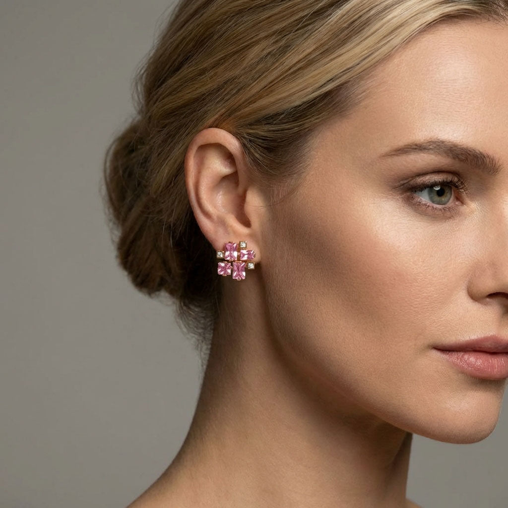 Model wearing a pink cubic zirconia geometric earring, close-up on a grey background