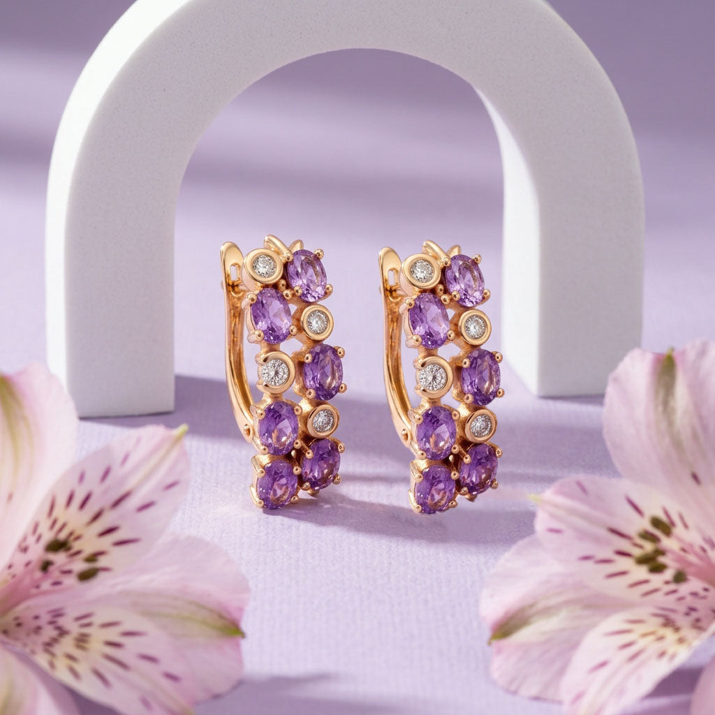 Pair of gold-plated earrings with violet stones on lilac fabric among pink flowers