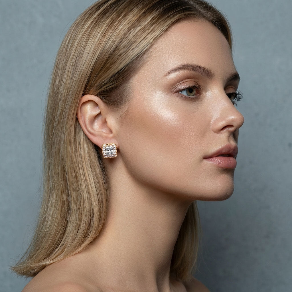 Woman wearing gold-plated square earrings, close-up against a light grey background