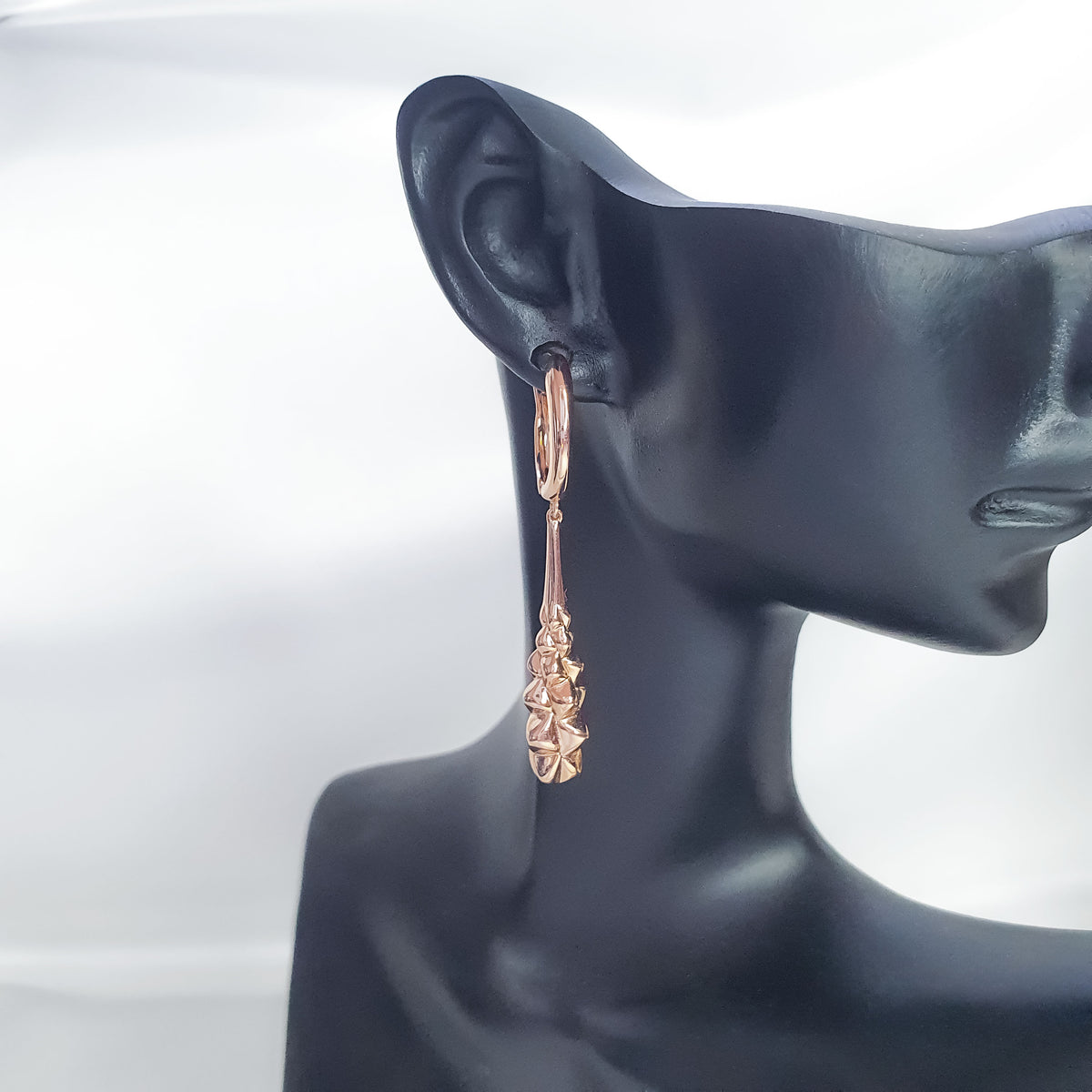 Long gold-plated earring on a black mannequin ear, side view showing its full length