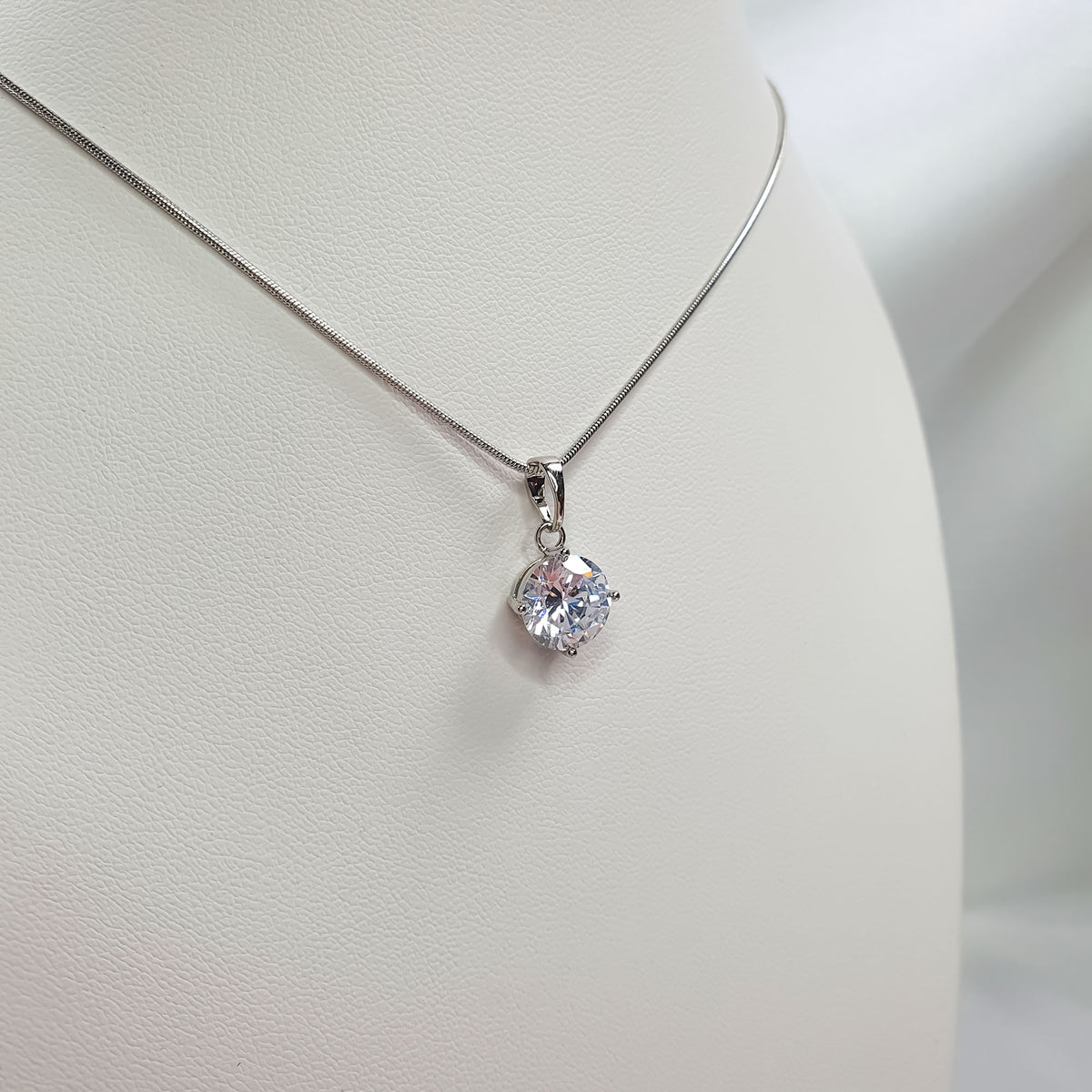 Silver-tone cubic zirconia pendant on a fine chain on a white display bust