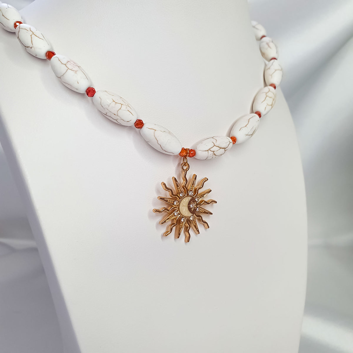 Close-up of gold-plated sun pendant with moon, cubic zirconia and orange spacer beads