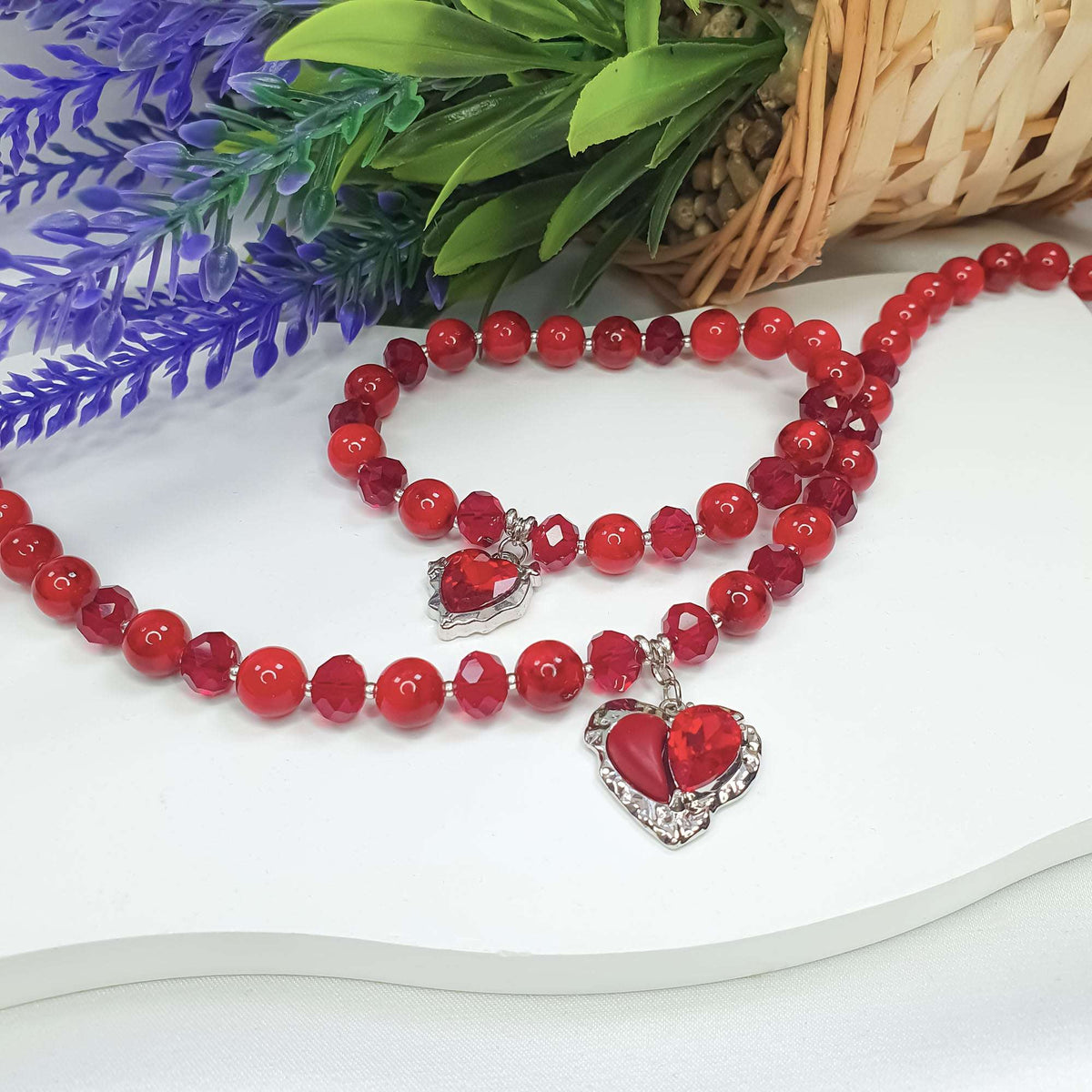 Red bead set with two heart charms beside lavender and a wicker basket