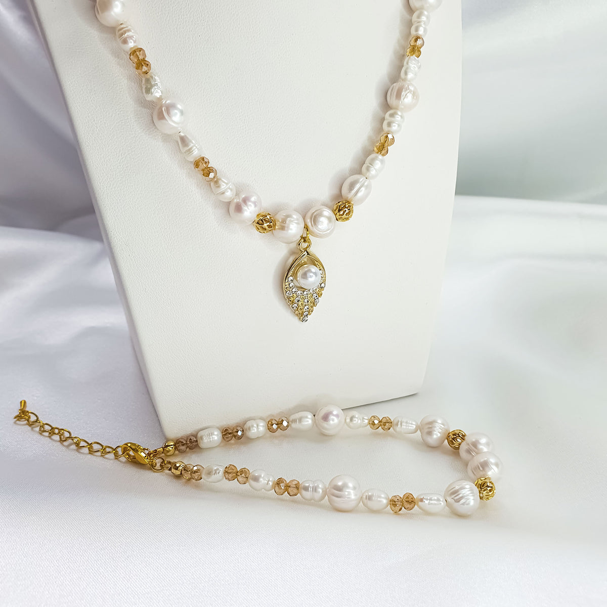 White pearl necklace with a leaf pendant and matching bracelet in gold tone