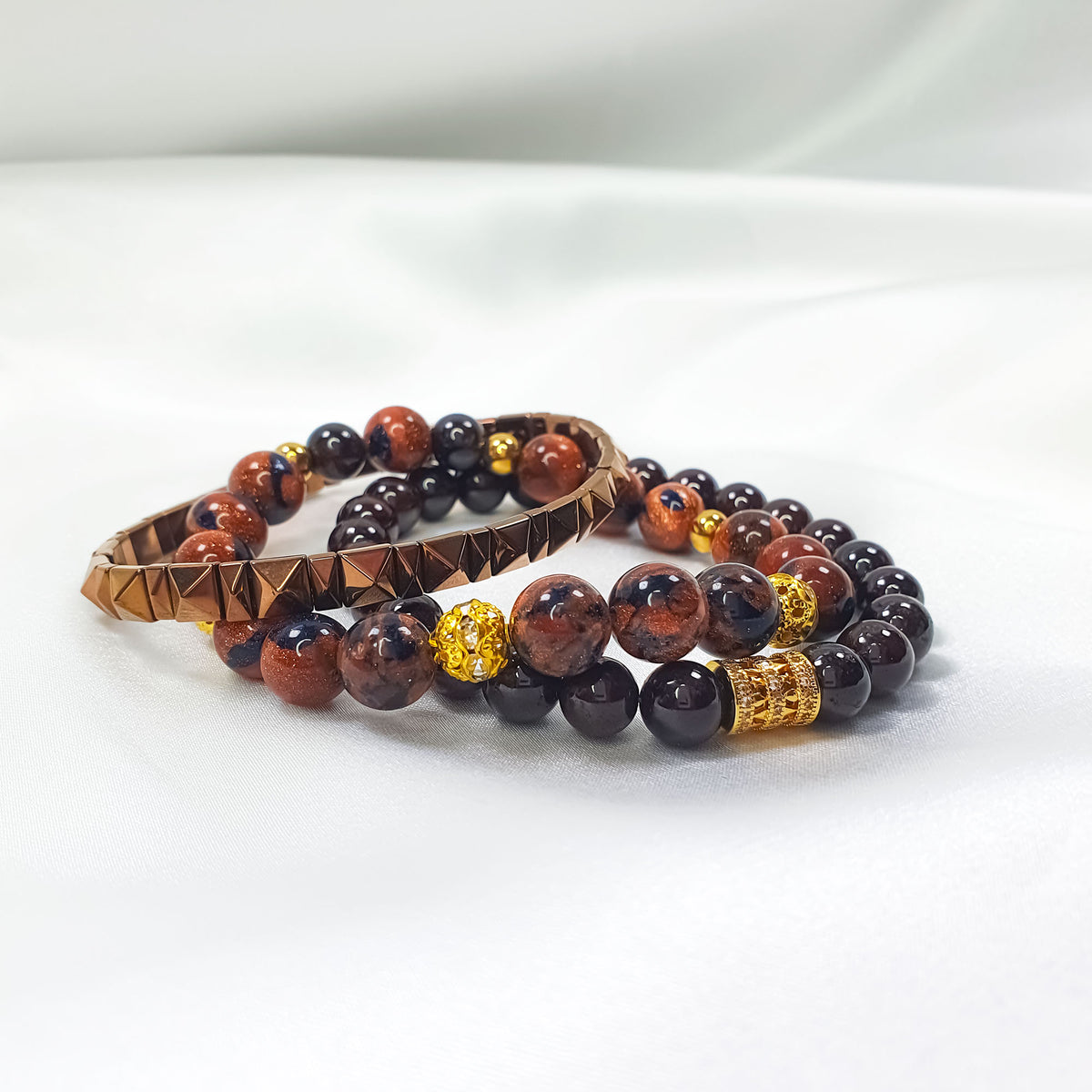 Bracelet trio on white satin, side view with pyramid beads and golden details