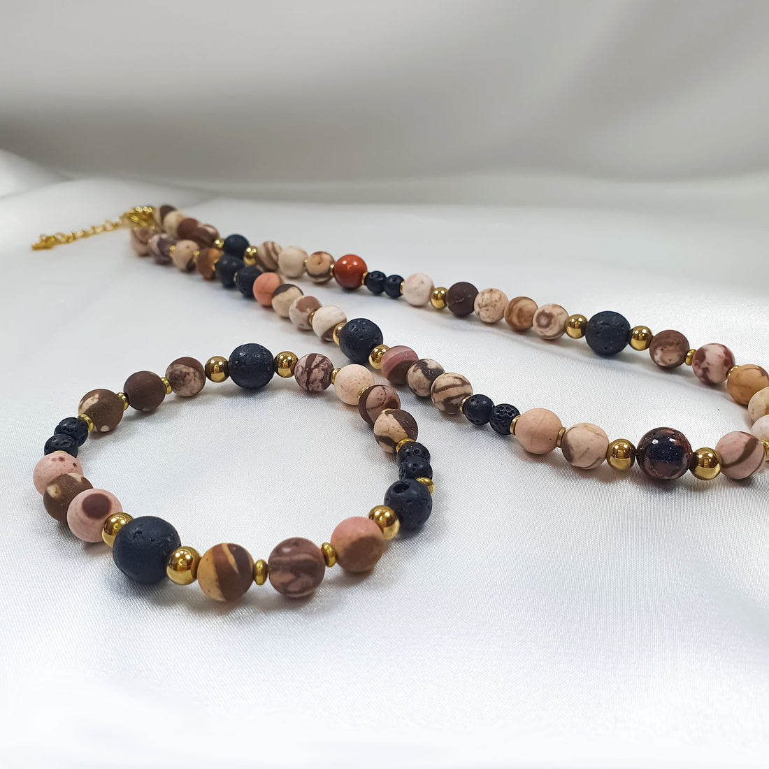 Stone necklace and bracelet on white satin with gold-tone clasp and extension chain