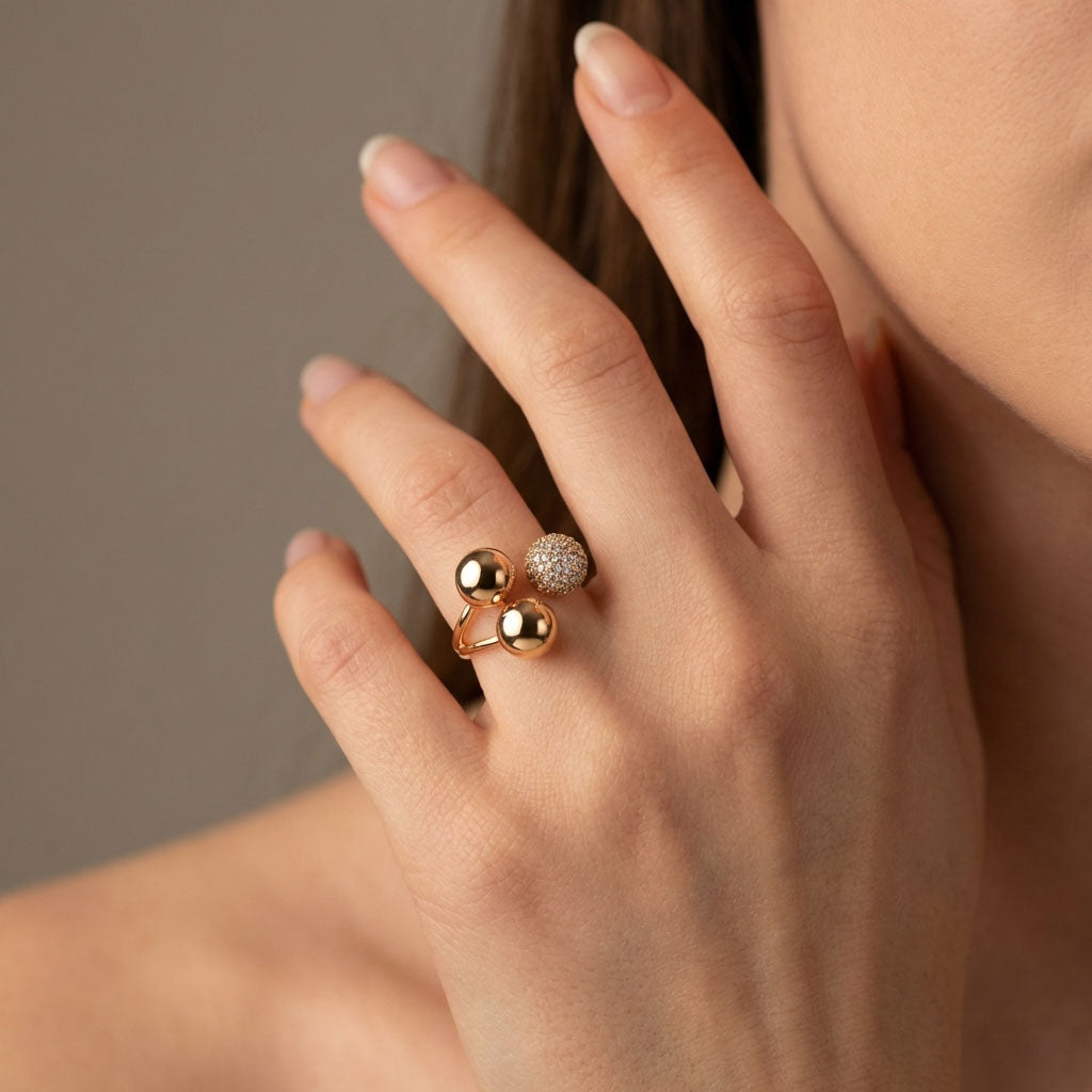 Woman wearing the gold-plated three-ball ring against a warm grey background