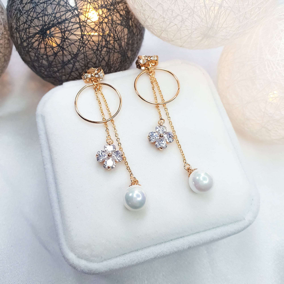 Clover and pearl earrings in a white gift box in warm light