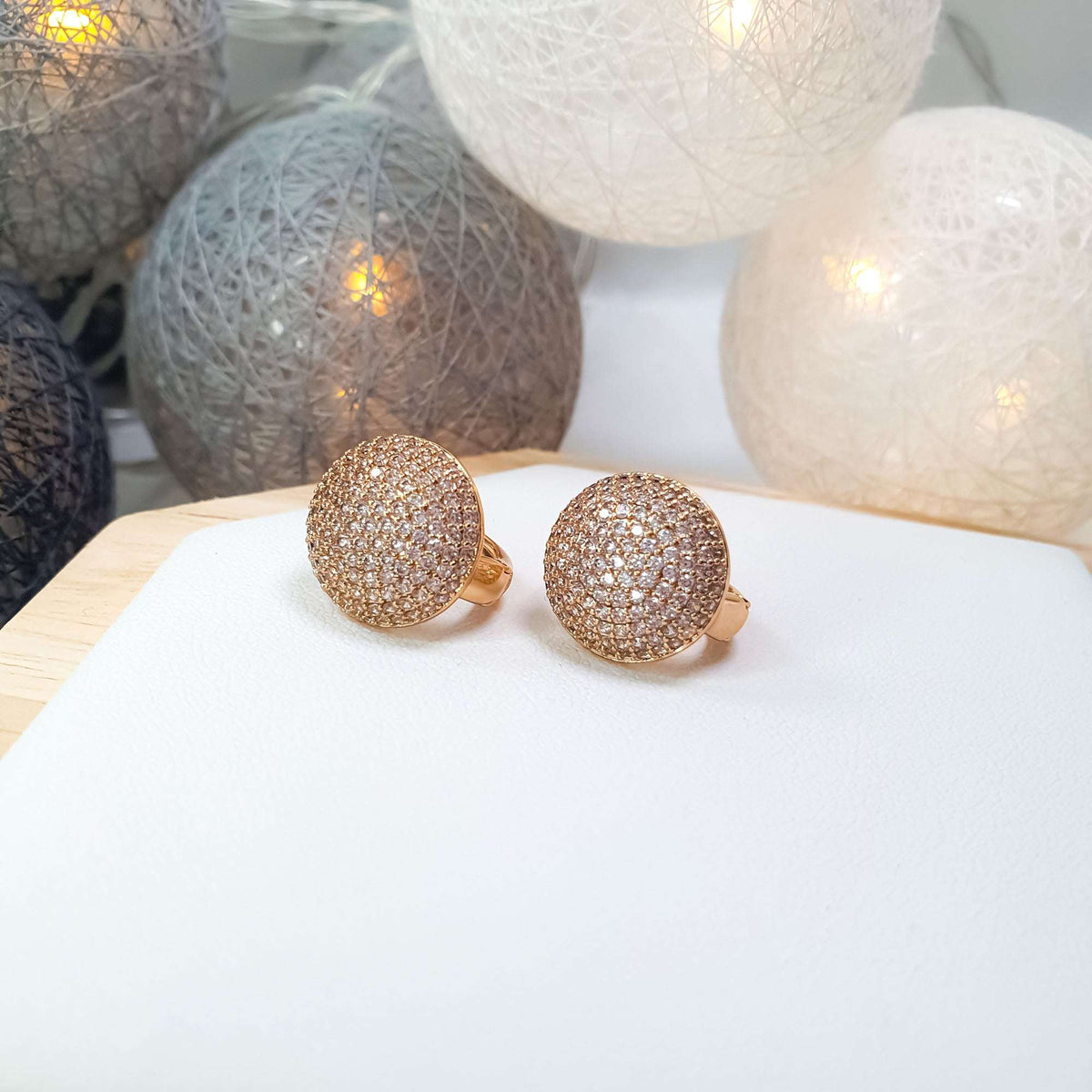 Pair of pavé dome earrings with cubic zirconia on a light surface