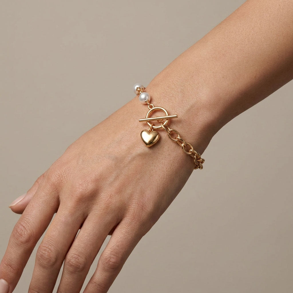 Gold-plated pearl bracelet with a heart charm on a model's wrist