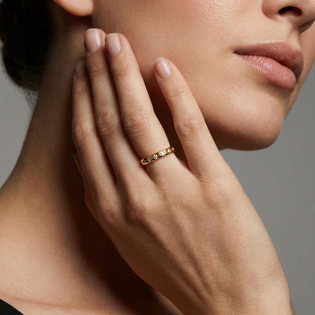 Model wearing a gold-tone cubic zirconia row ring, hand raised to her face