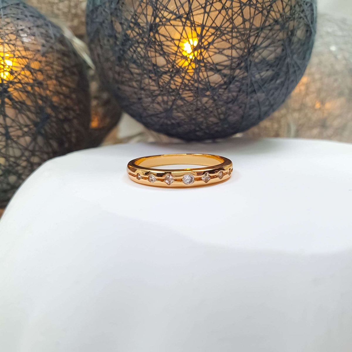 Front view of a gold-tone ring with a row of cubic zirconia, warm light