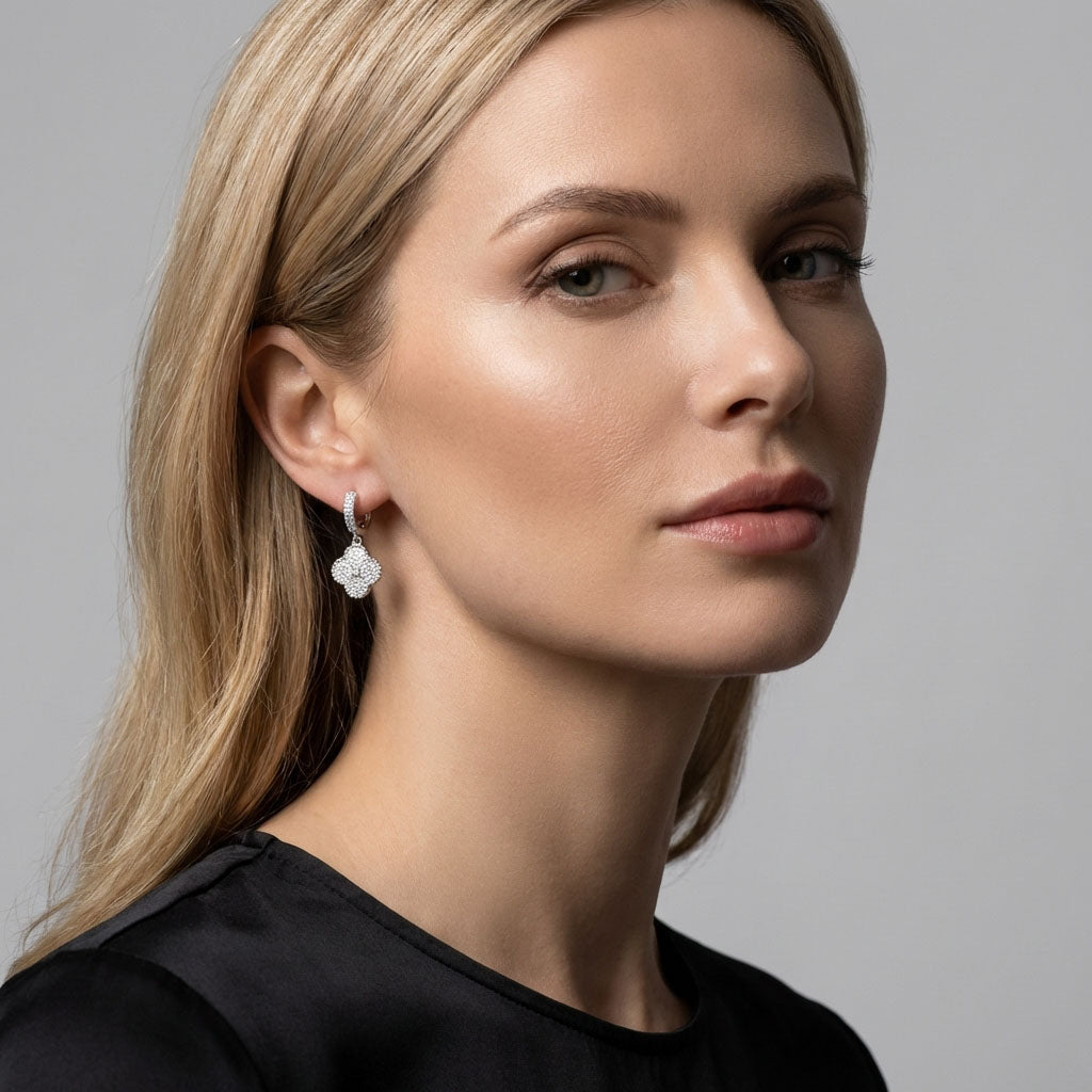 Model in a black top wearing a dangling silver-tone clover earring