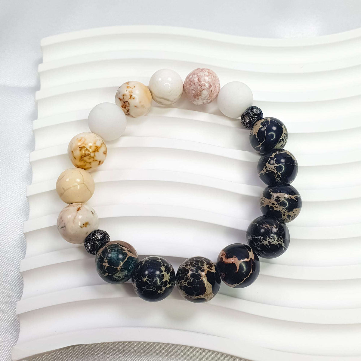 Close-up of pale nephrite beads, dark stones and black sparkling spacers