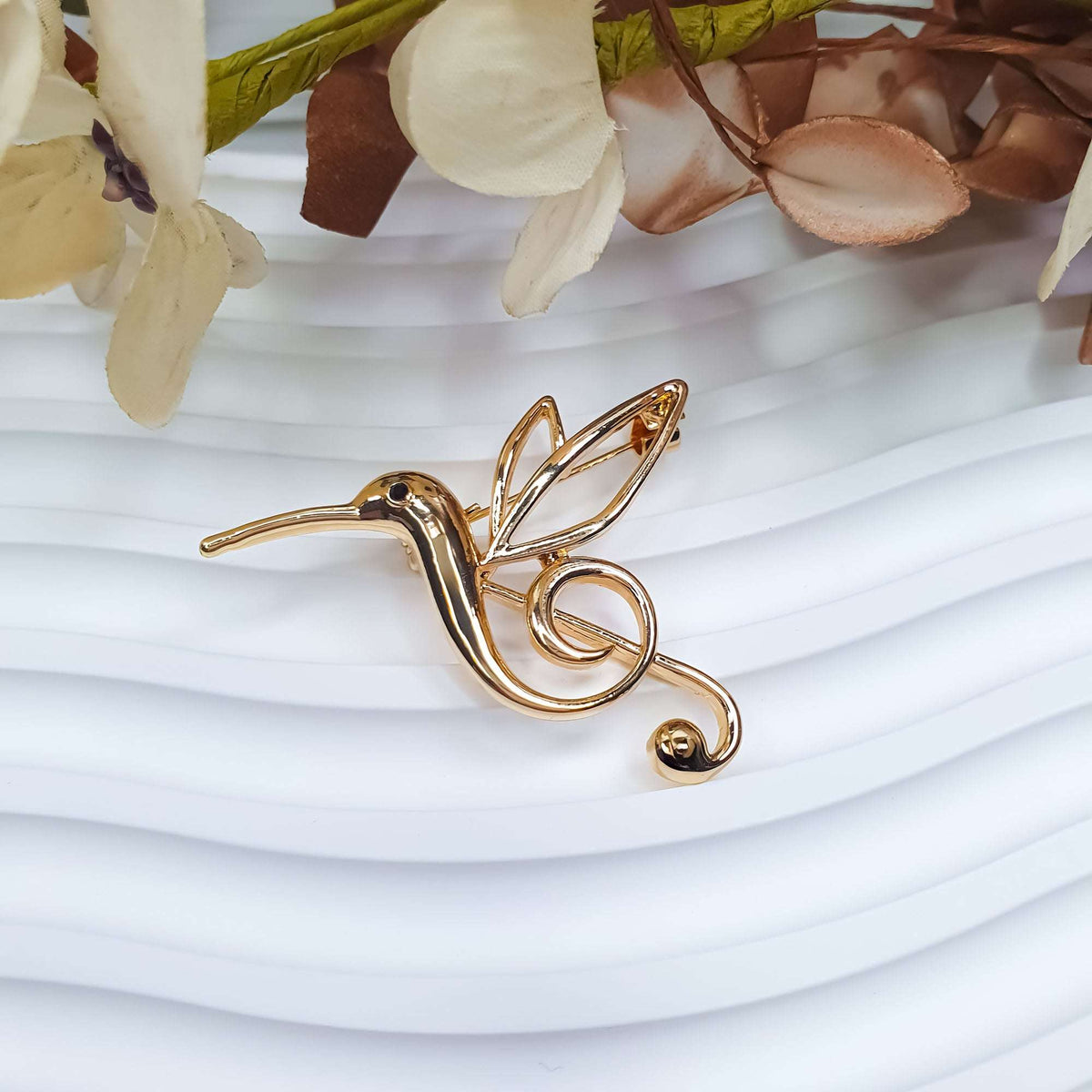 Stylised hummingbird brooch in side view with its pin fastening visible