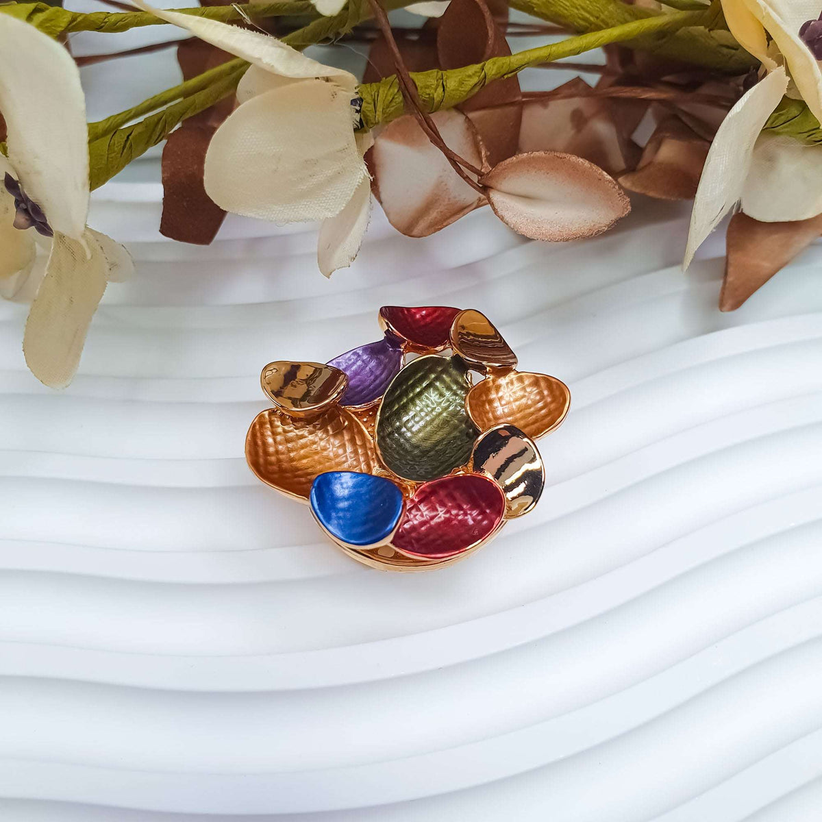 Multicolour enamel brooch seen at an angle with a green centre
