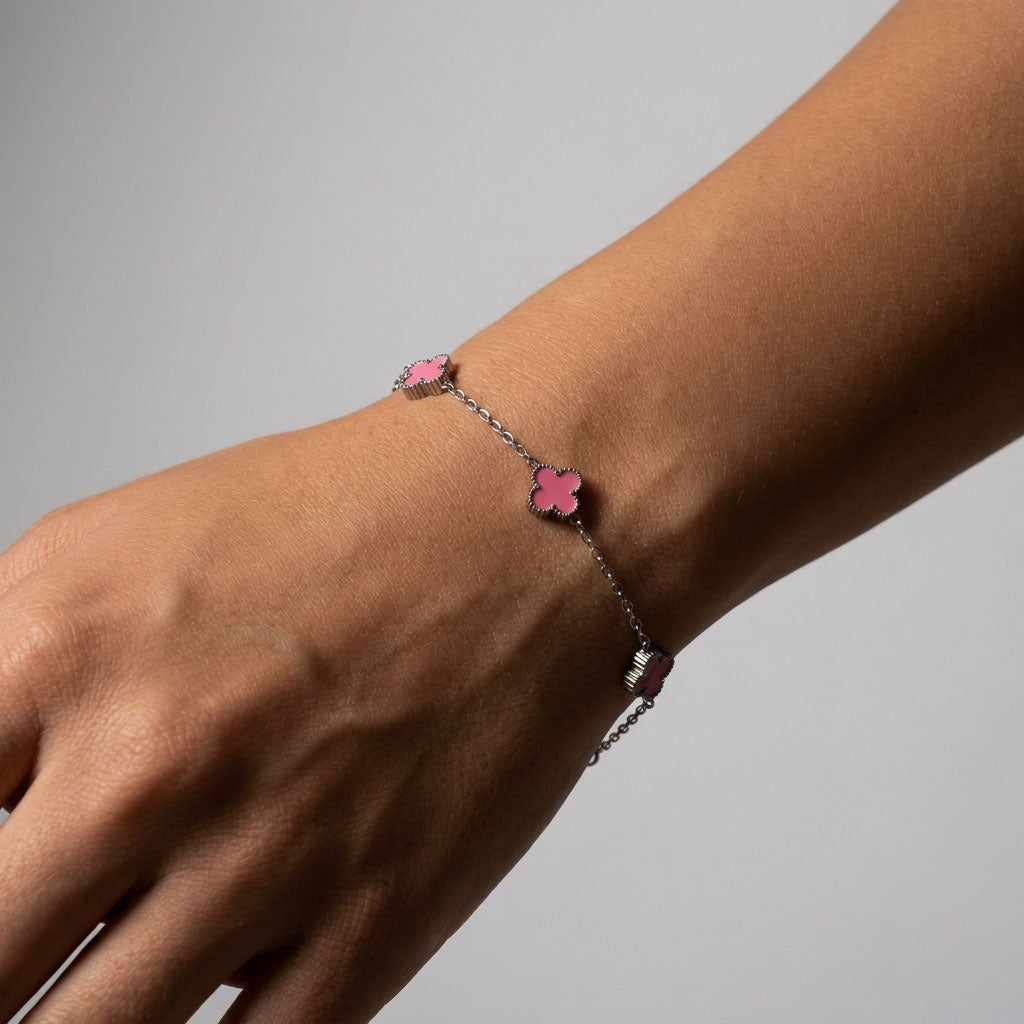 Pink clover bracelet on a woman's wrist against a light grey background