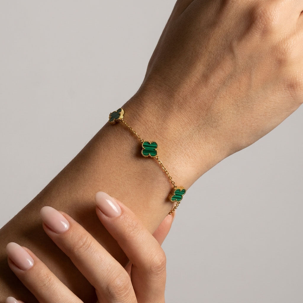 Green clover bracelet on a model's wrist with a fine gold-plated chain