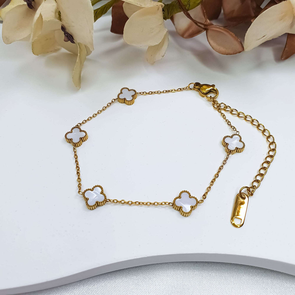 White clover bracelet with adjustable extension chain on a light surface