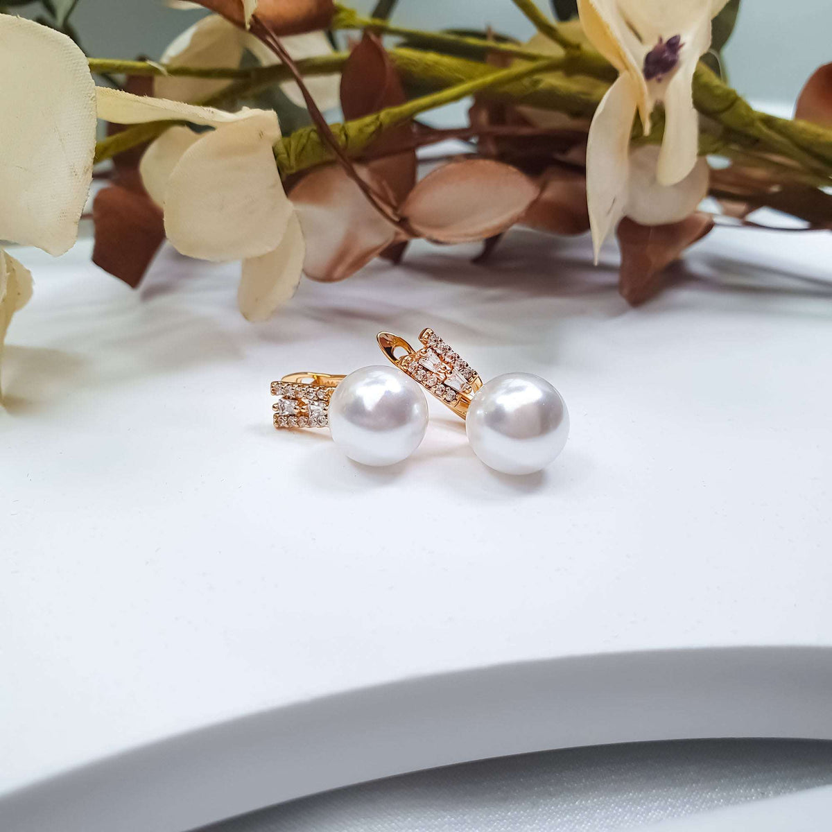 White faux pearl earrings with a row of cubic zirconia on gold-tone leverbacks