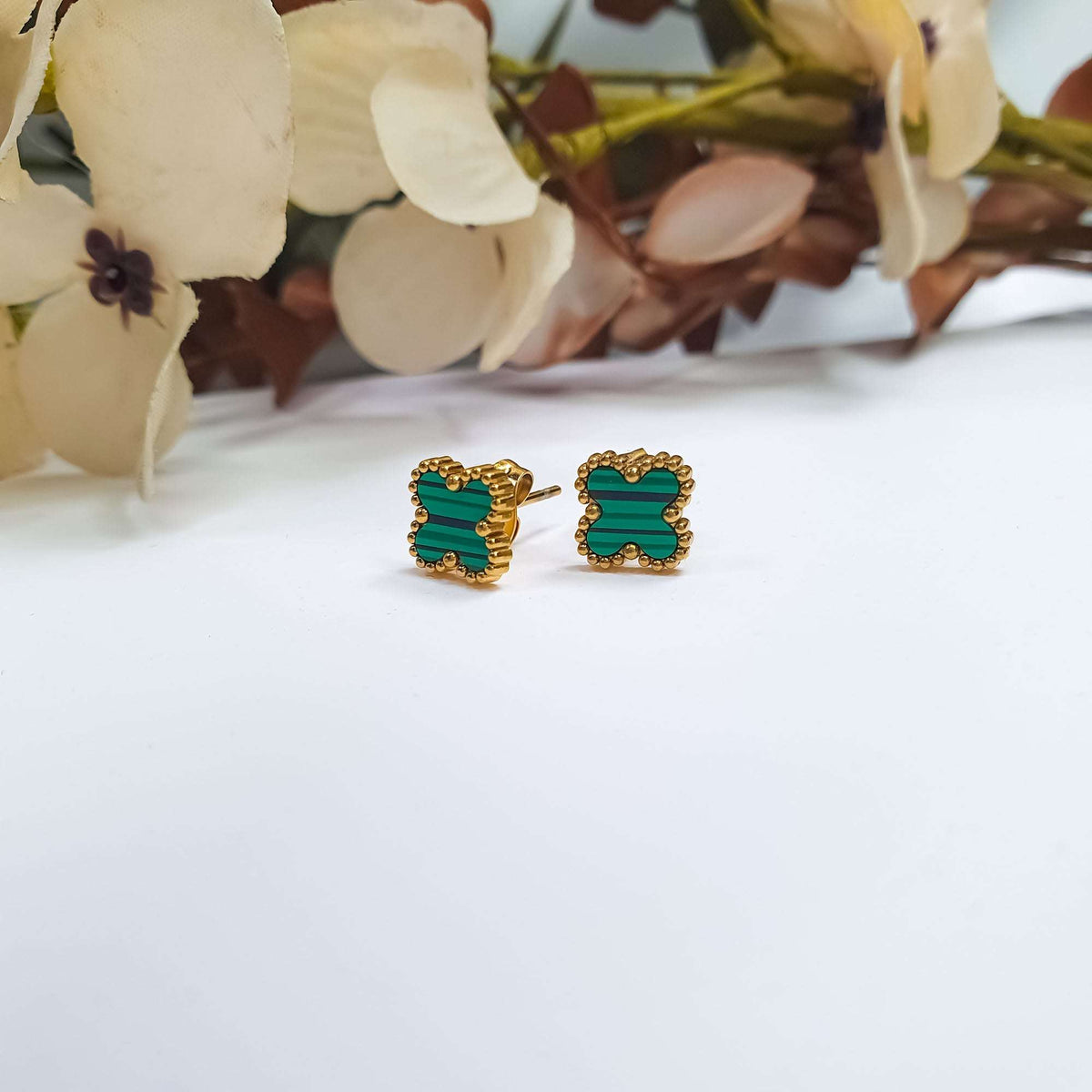 Green enamel clover earrings at an angle, gold-tone post and back visible