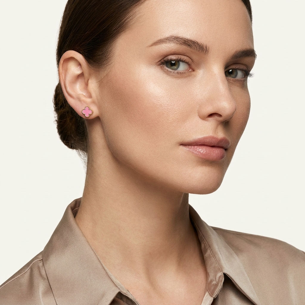Model wearing a small pink enamel clover stud with a gold-tone rim