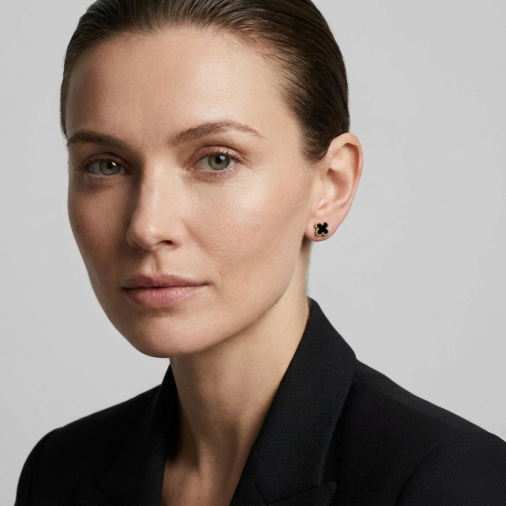 Black clover stud with gold-tone beading in a woman's ear, close-up