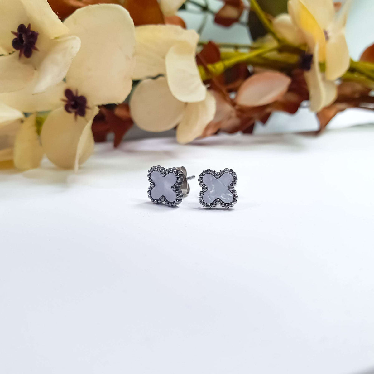 Pearly white clover studs with dark silver-tone beading beside dried flowers