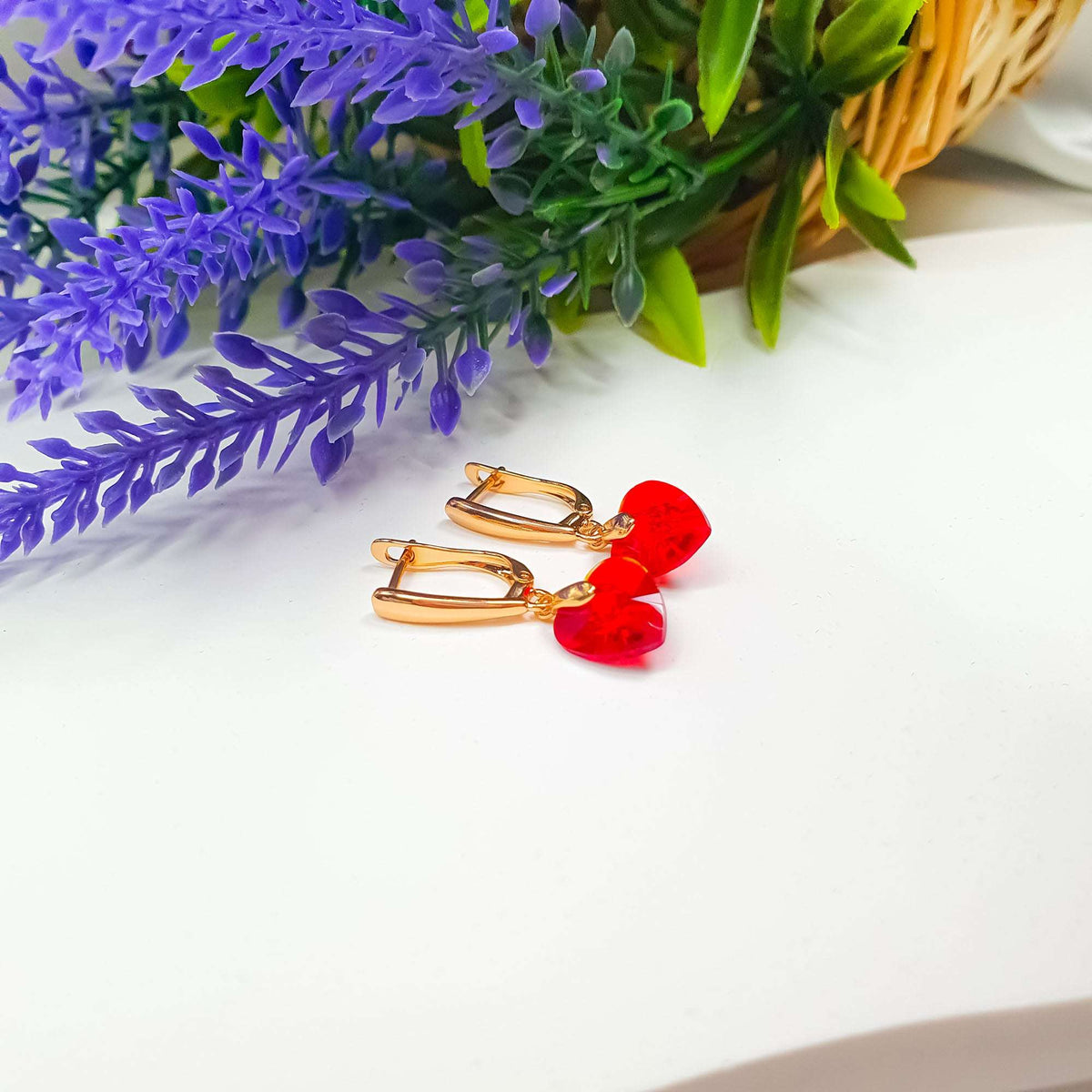 Red crystal heart earrings beside lavender, showing the gold-tone clasp