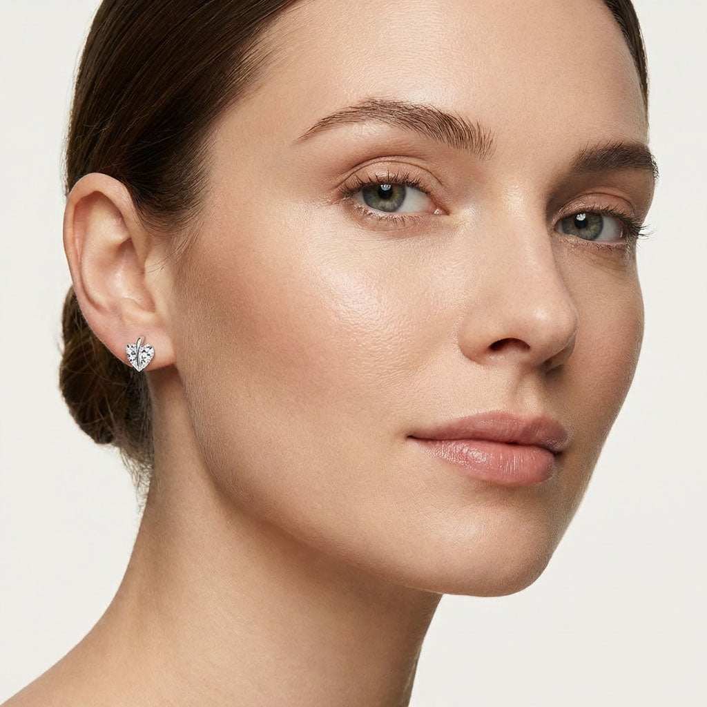 Model wearing silver-tone studs with a clear heart cubic zirconia